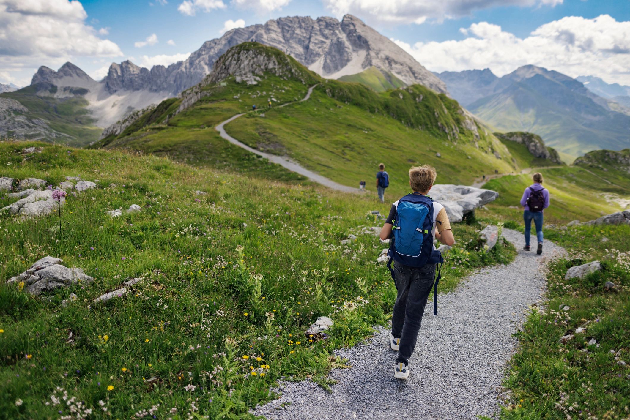 Family hiking on a high mountain path in the Alps