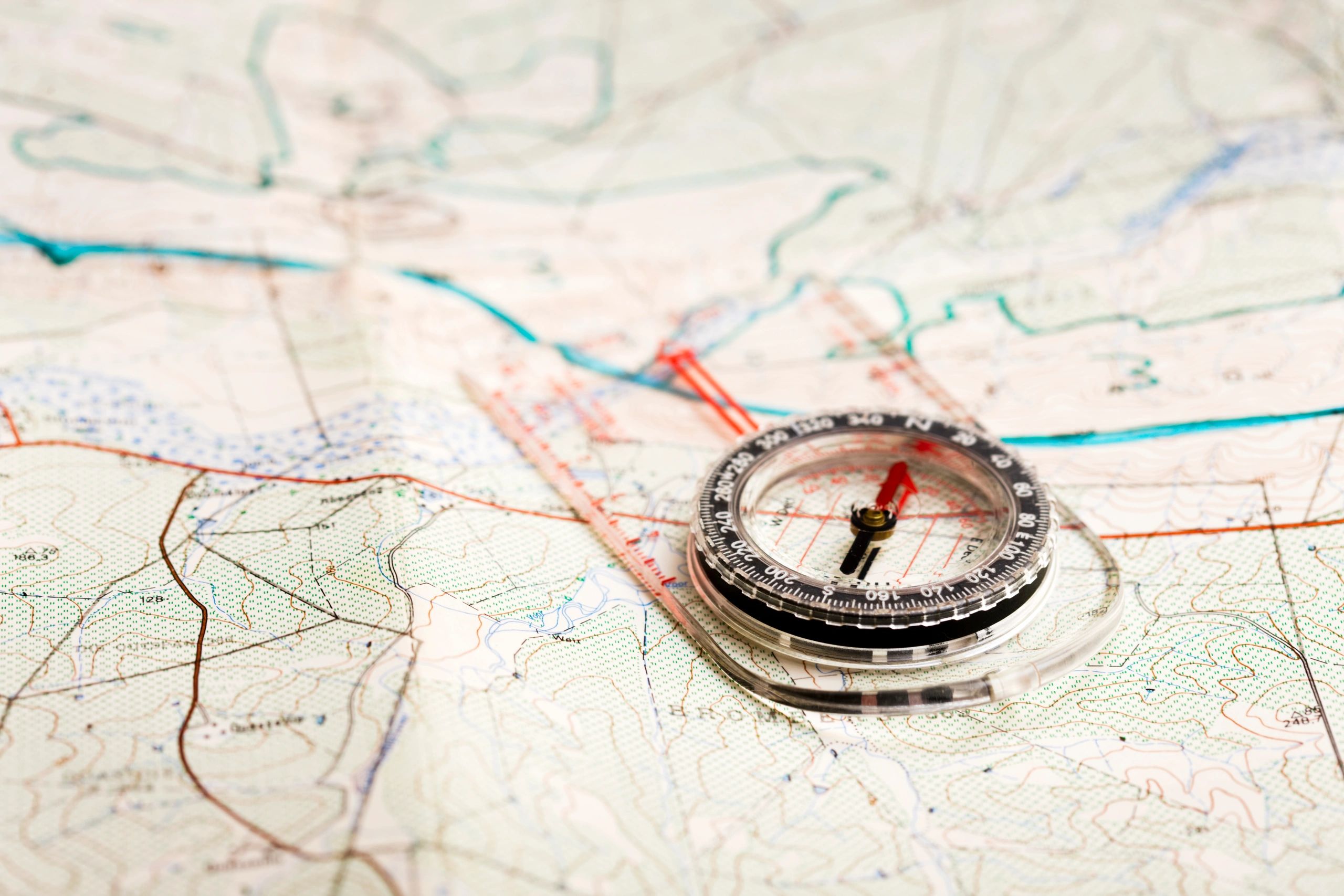 Compass positioned on a detailed topographic map, illustrating navigation tools for hikers and mountaineers in planning outdoor adventures.
