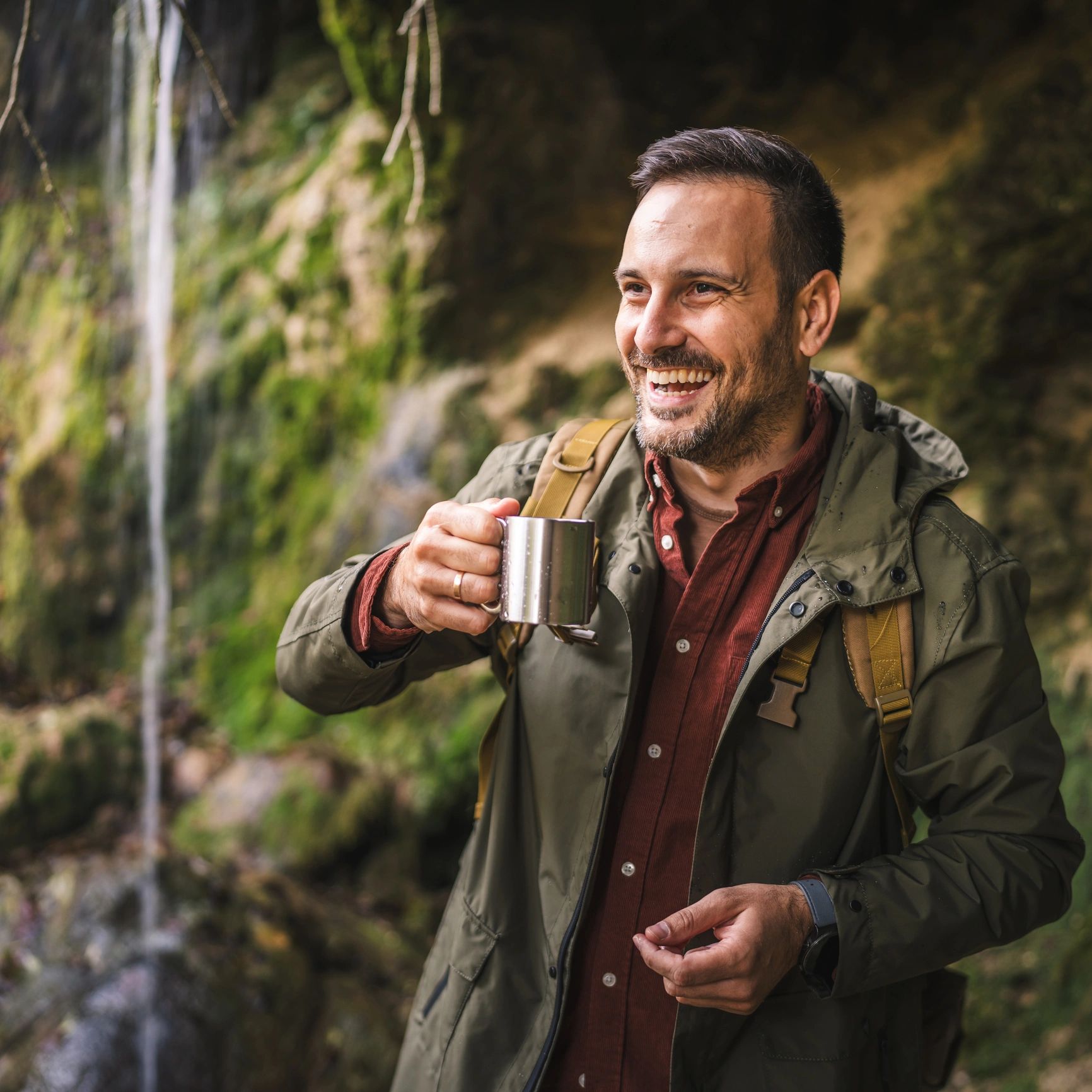 Portrait of a hiker drinking water near a waterfall