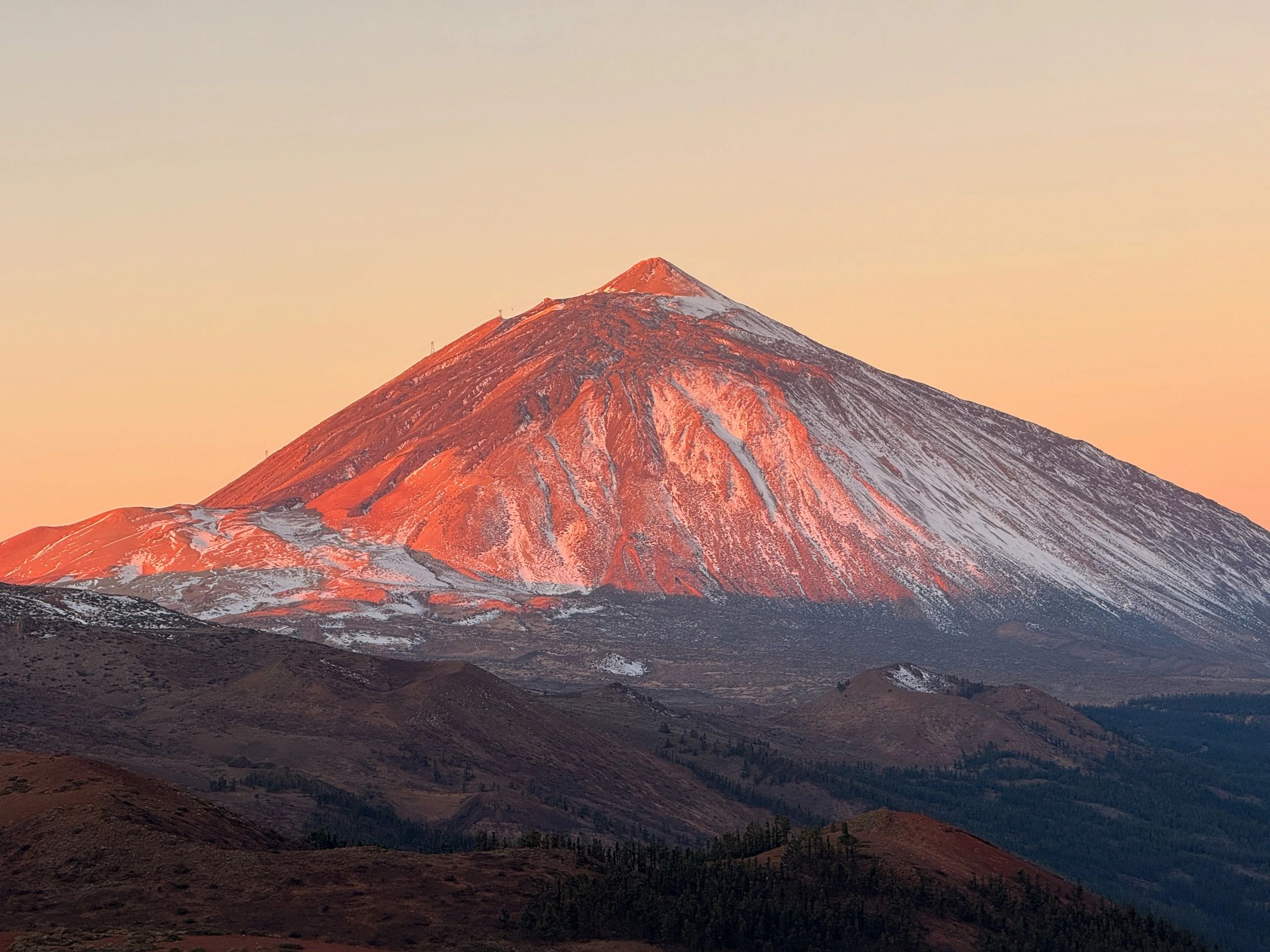 Snow-capped mountain at sunset, showcasing vibrant orange and pink hues, representing a peak for hiking and mountaineering enthusiasts.