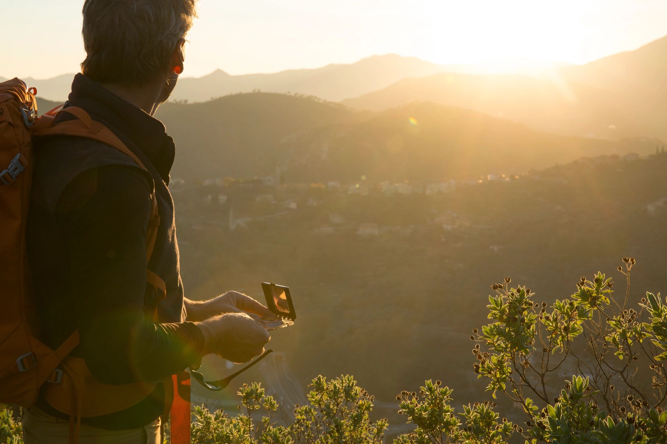 Hiker checking a compass in warm evening light