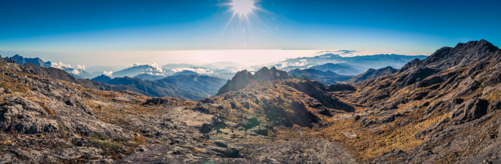 Panoramic view of Mount Wilhelm at sunrise, showcasing rugged mountain terrain and distant peaks in Papua New Guinea, emphasizing the remote and scenic beauty important for trekkers and climbers.