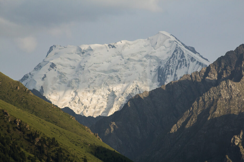 Snow-capped Jengish Chokusu (Pobeda Peak) towering over surrounding rugged terrain in the Tian Shan mountain range, Kyrgyzstan.