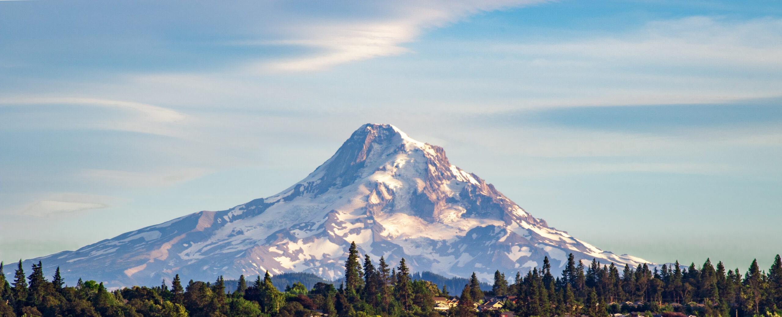 Snow-covered Mount Hood summit and forested slopes, a Pacific Northwest climbing destination.