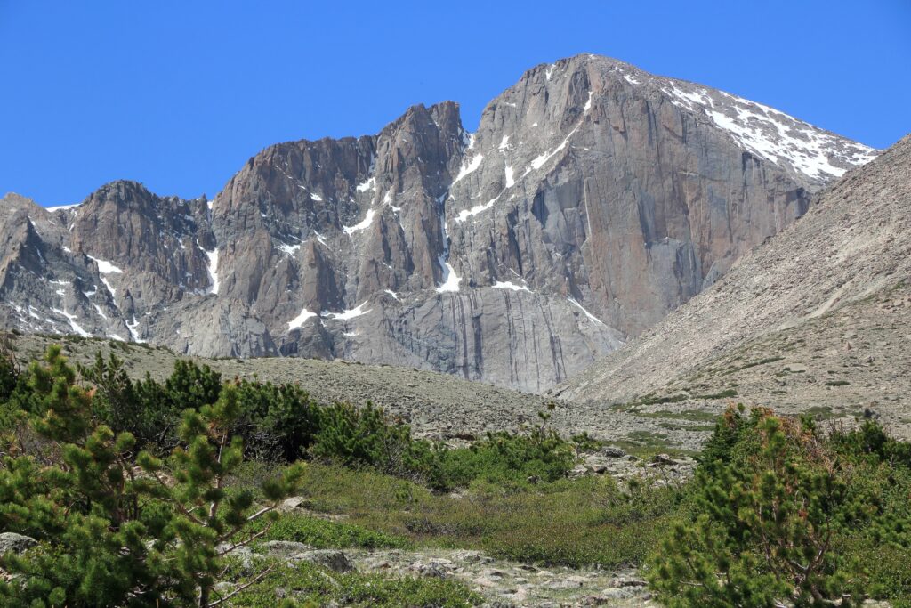 Longs Peak towering above rocky terrain and alpine vegetation in Rocky Mountain National Park, Colorado, showcasing its iconic summit and rugged features.