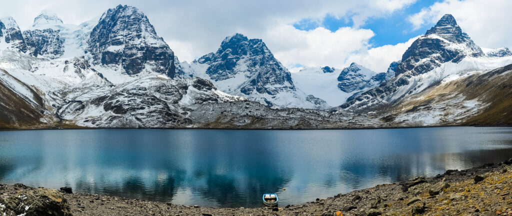 Panoramic view of Condoriri and Alpamayo mountains reflecting in a serene lake at the Condoriri base camp, La Paz, Bolivia, showcasing the dramatic landscape of the Andes.