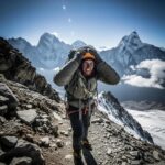 Mountain climber experiencing altitude sickness while navigating a high-altitude landscape with snow-capped peaks in the background.