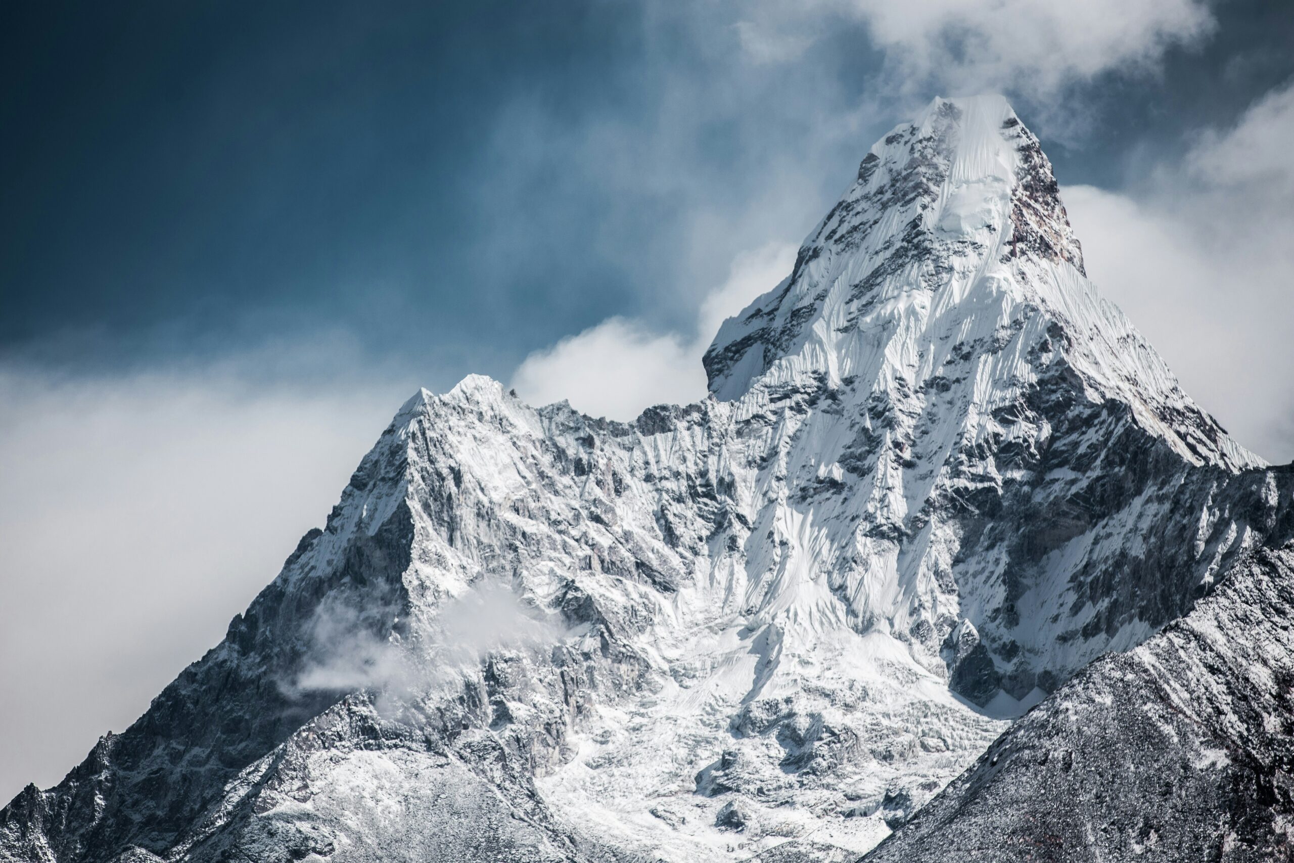 Snow-covered peak of Mount Everest under a cloudy sky, highlighting the challenges climbers face due to unpredictable weather conditions.
