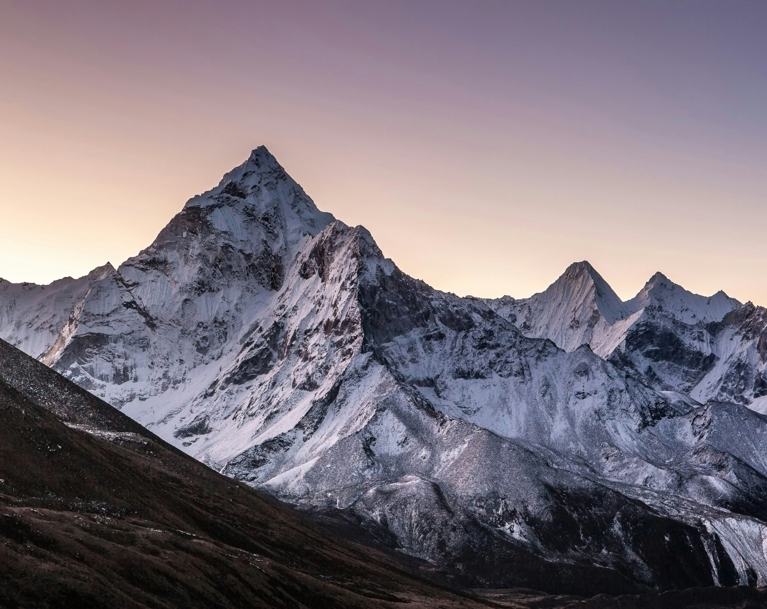 Snow-capped peaks of Mount Everest at sunset, highlighting the challenging terrain and weather conditions crucial for climbers' safety and expedition planning.