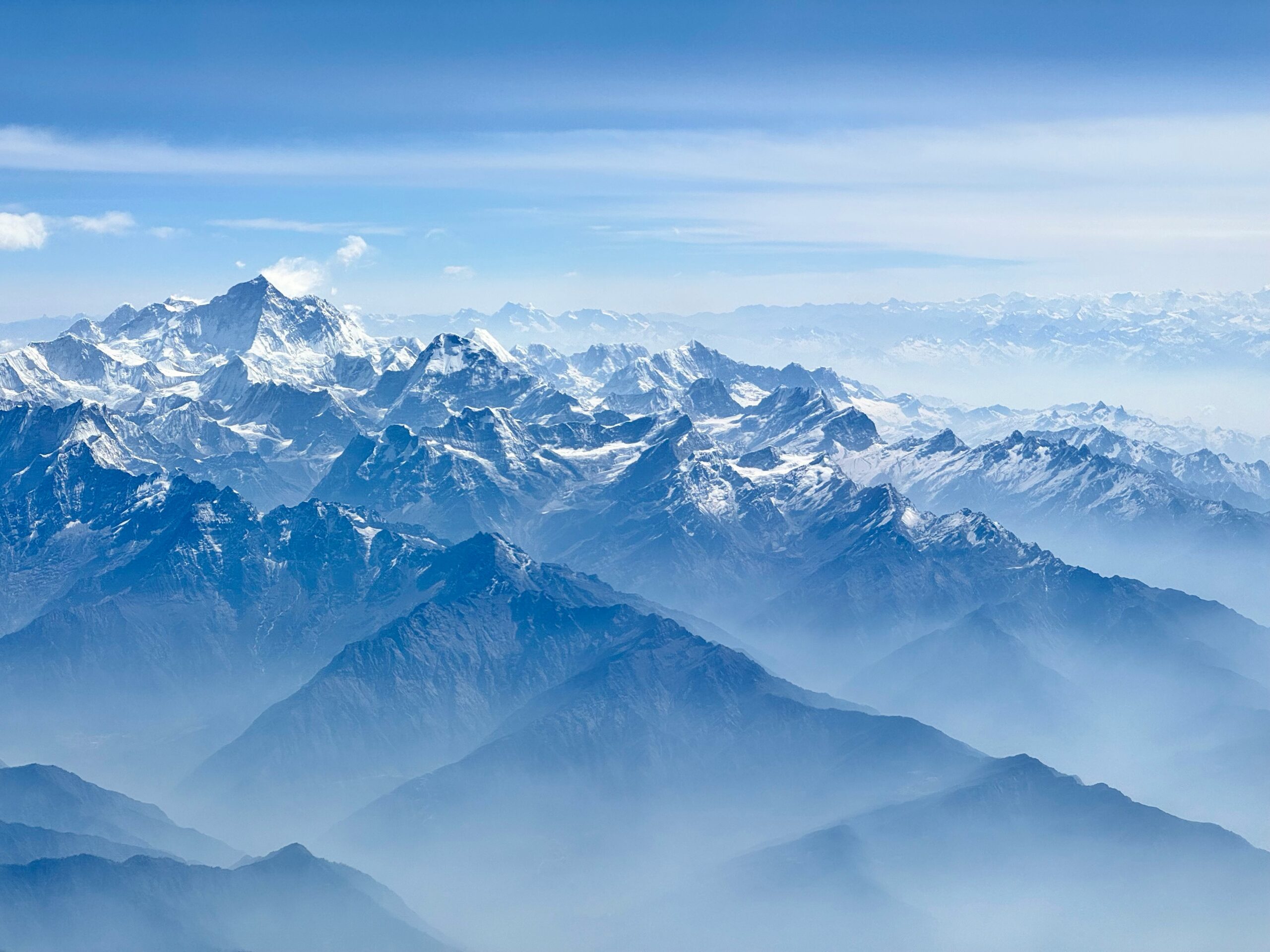 Snow-capped peaks of Mount Everest and surrounding Himalayas under clear blue sky, illustrating the majestic landscape crucial for climbers' safety and weather considerations during expeditions.