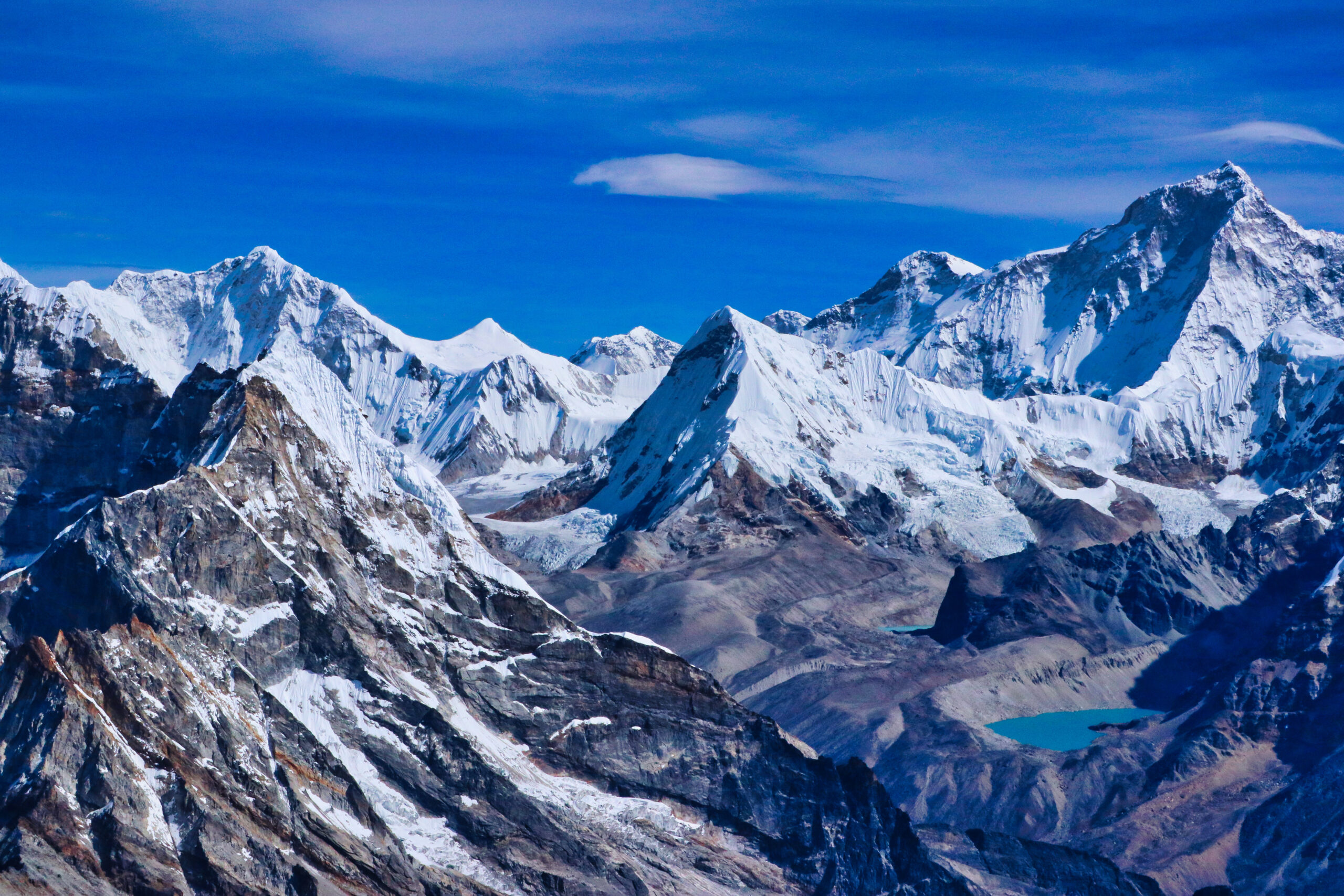 Wide mountain landscape showing alpine peaks under dramatic cloud cover, representing the global scope of Global Summit Guide's 500-peak directory across seven continents