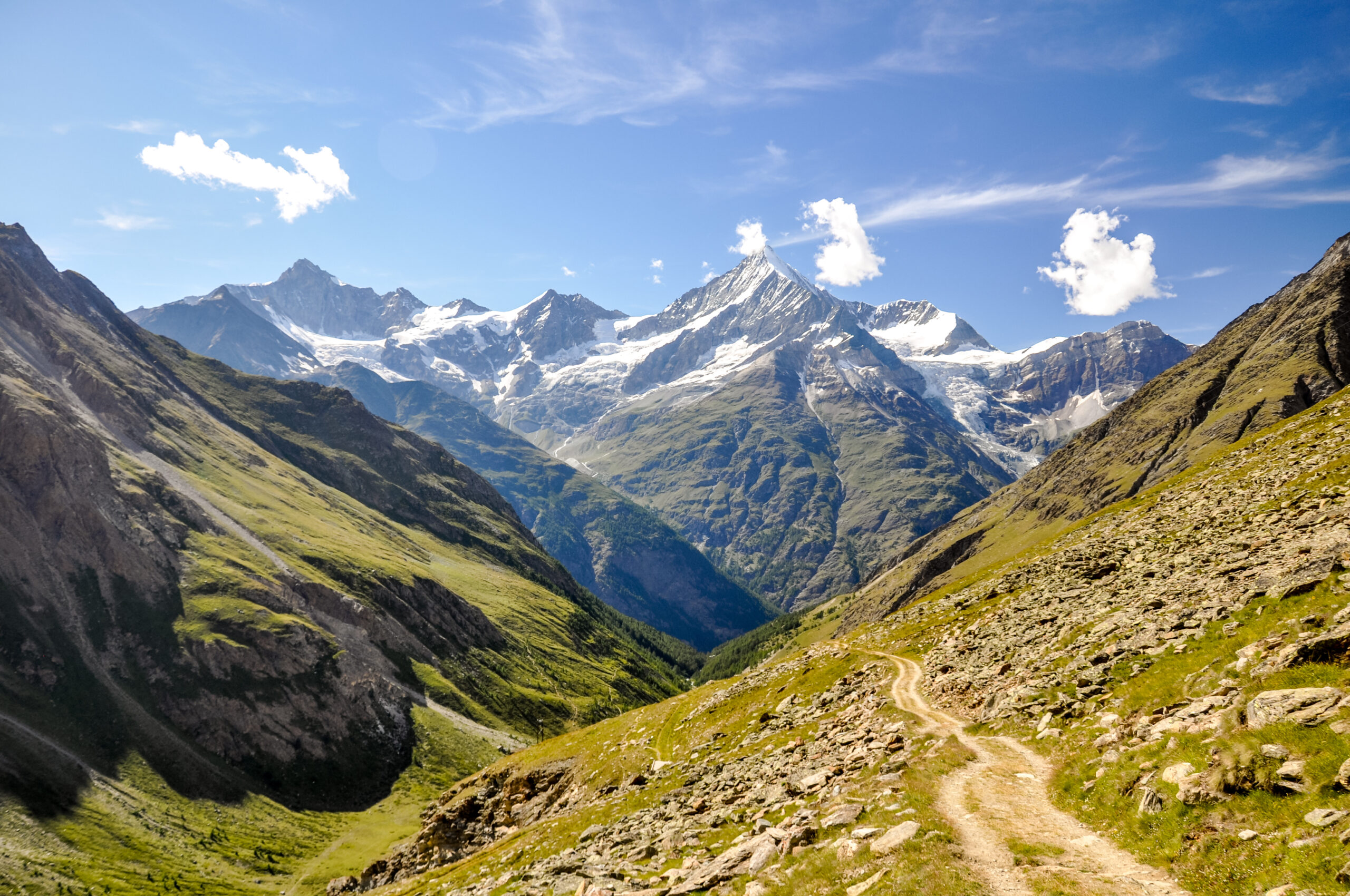 The Weisshorn pyramid rising above the Mattertal valley, showing the rock and snow-covered ridges that require full mountaineering equipment including B2 or B3 boots, automatic crampons, a single technical ice axe, harness, helmet, and a 50 to 60 meter rope