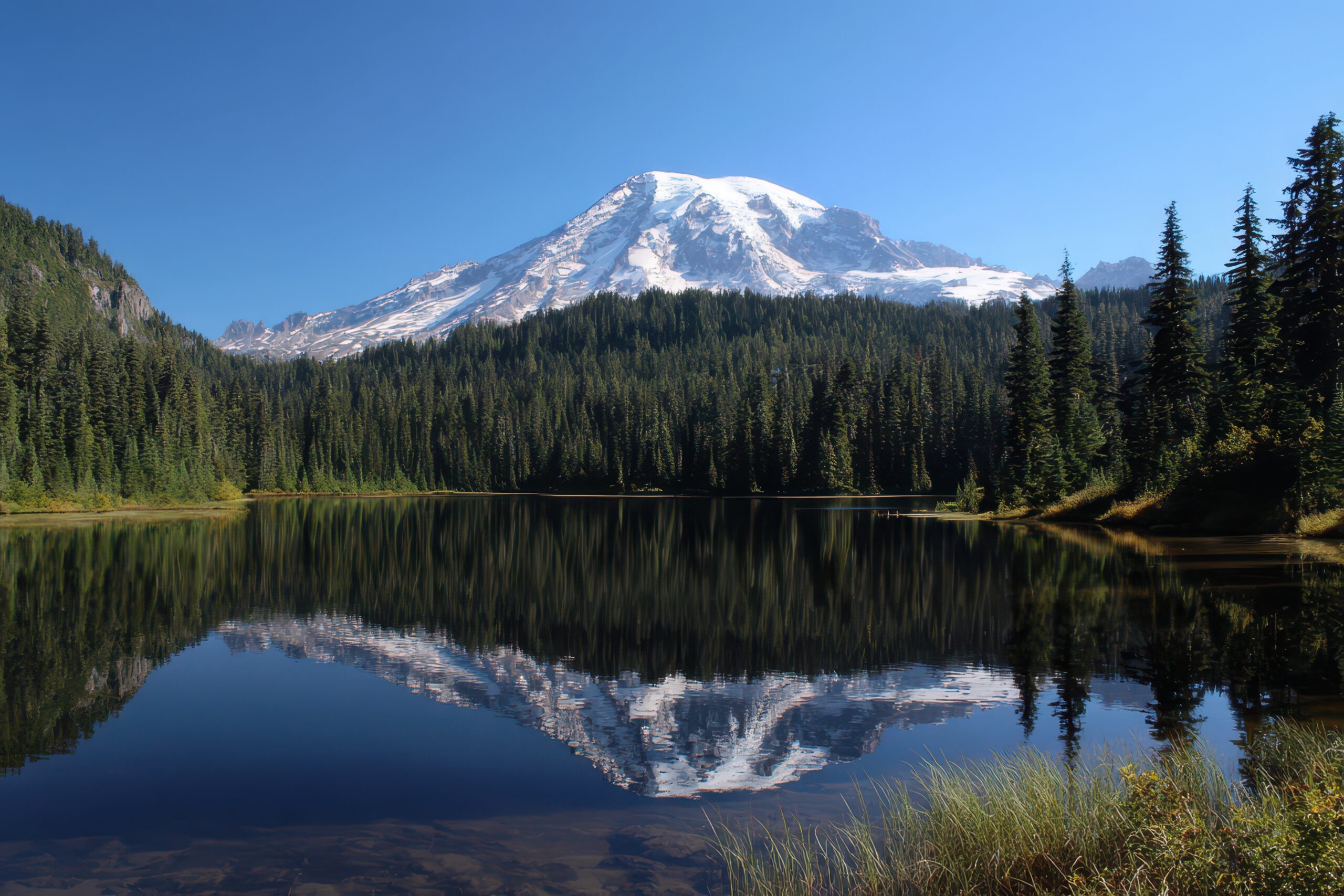 Snow-capped Mount Rainier reflected in a mountain lake, illustrating Seven Summits climbing costs.