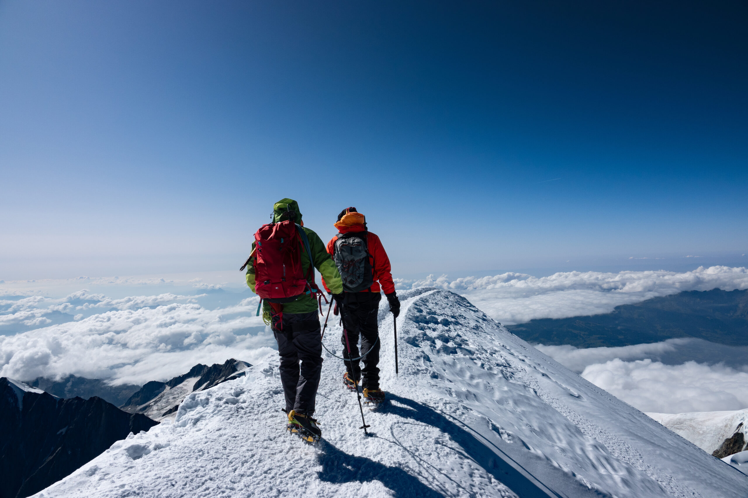 Climbers ascending the Bosses Ridge toward Mont Blanc's 4,810m summit with dawn lighting — representative of the Goûter Route summit day timing and alpine conditions
