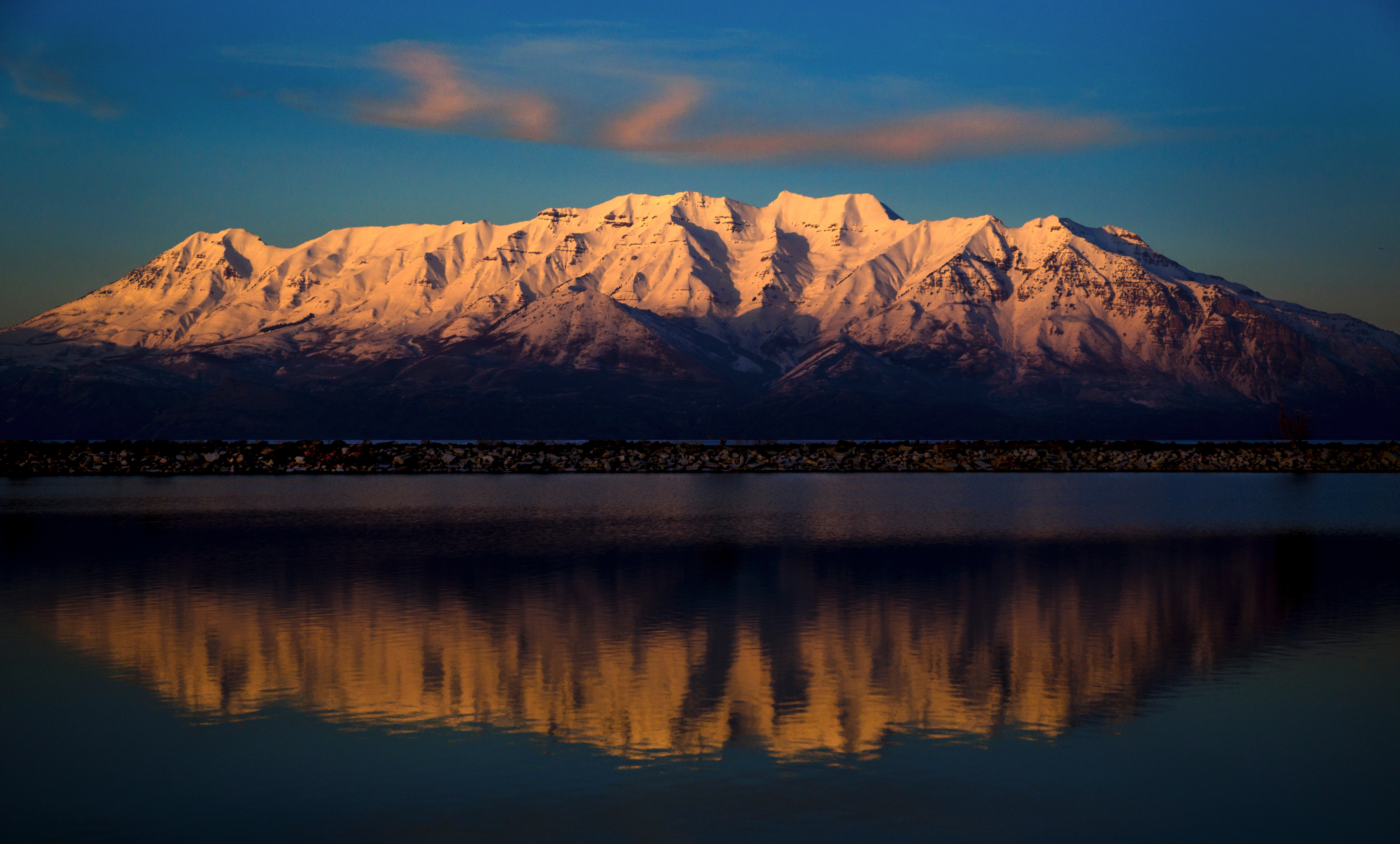 Mount Timpanogos at sunrise reflected in Utah Lake showing the snow-capped jagged ridgeline of Utah's most iconic Wasatch Range peak &mdash; Mount Timpanogos at 11,752 feet is the second-highest peak in the Wasatch Range after Mount Nebo and is by far the most-climbed serious mountain in Utah with two well-maintained trails (Timpooneke and Aspen Grove) leading to its summit through alpine meadows wildflower fields and the famous Mount Timpanogos glacier the only remaining glacier in Utah's mountains