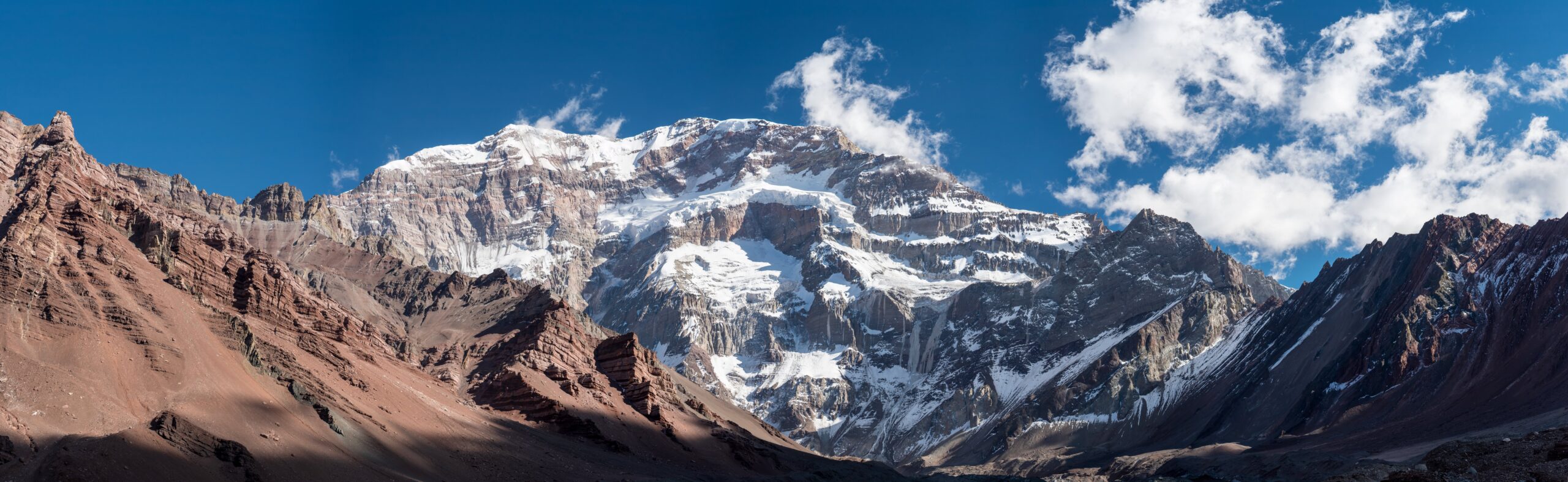 Climber carrying a loaded expedition pack on a high-altitude slope, the core Aconcagua training demand