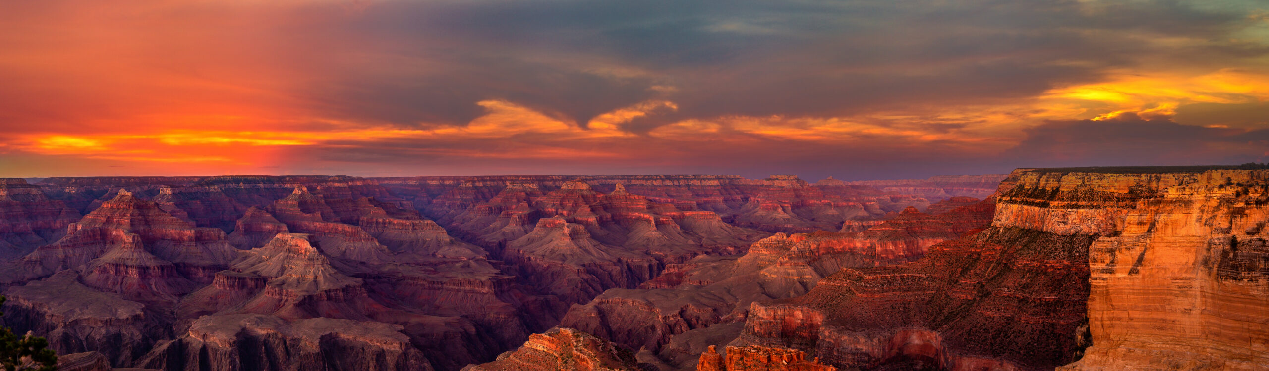 The Grand Canyon at sunset, the layered rock walls glowing red and gold as light fades across the canyon