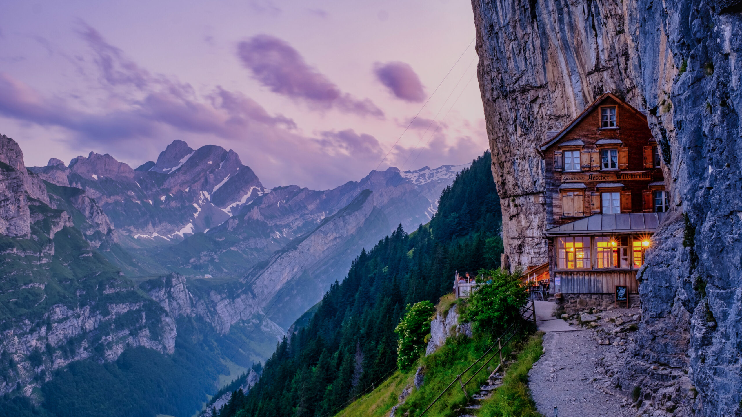 Hikers on an alpine trail approaching a mountain hut on a multi-day hut-to-hut route