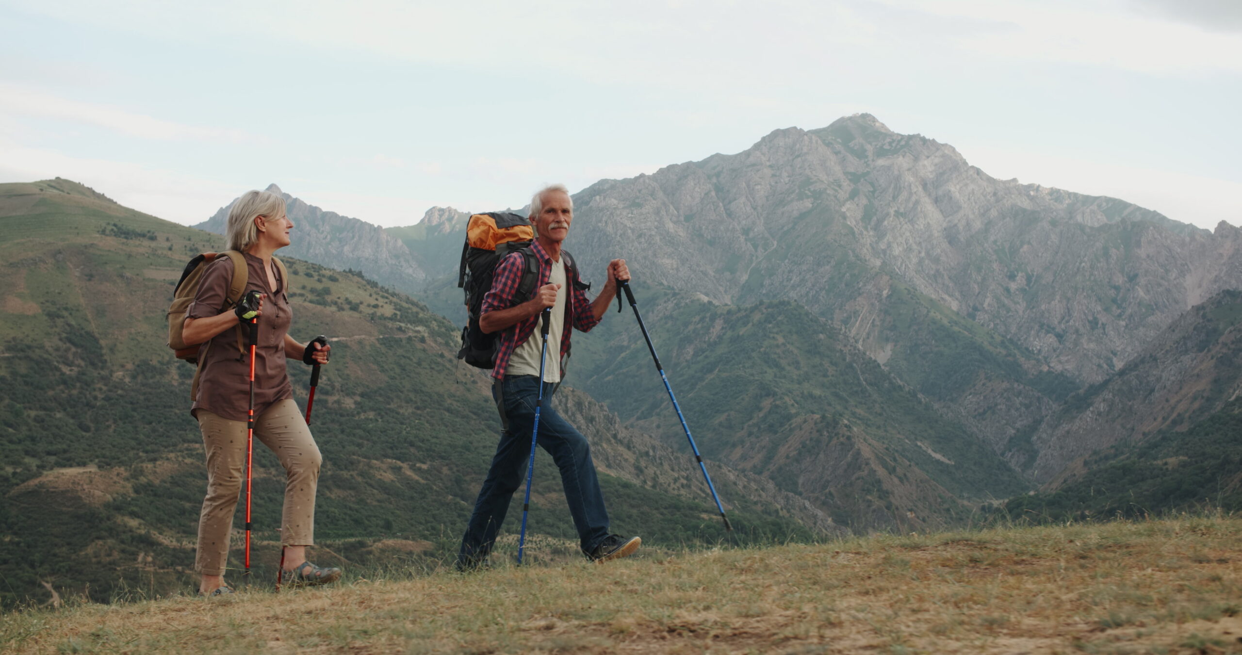 An older mountaineer moving strongly along a high ridge