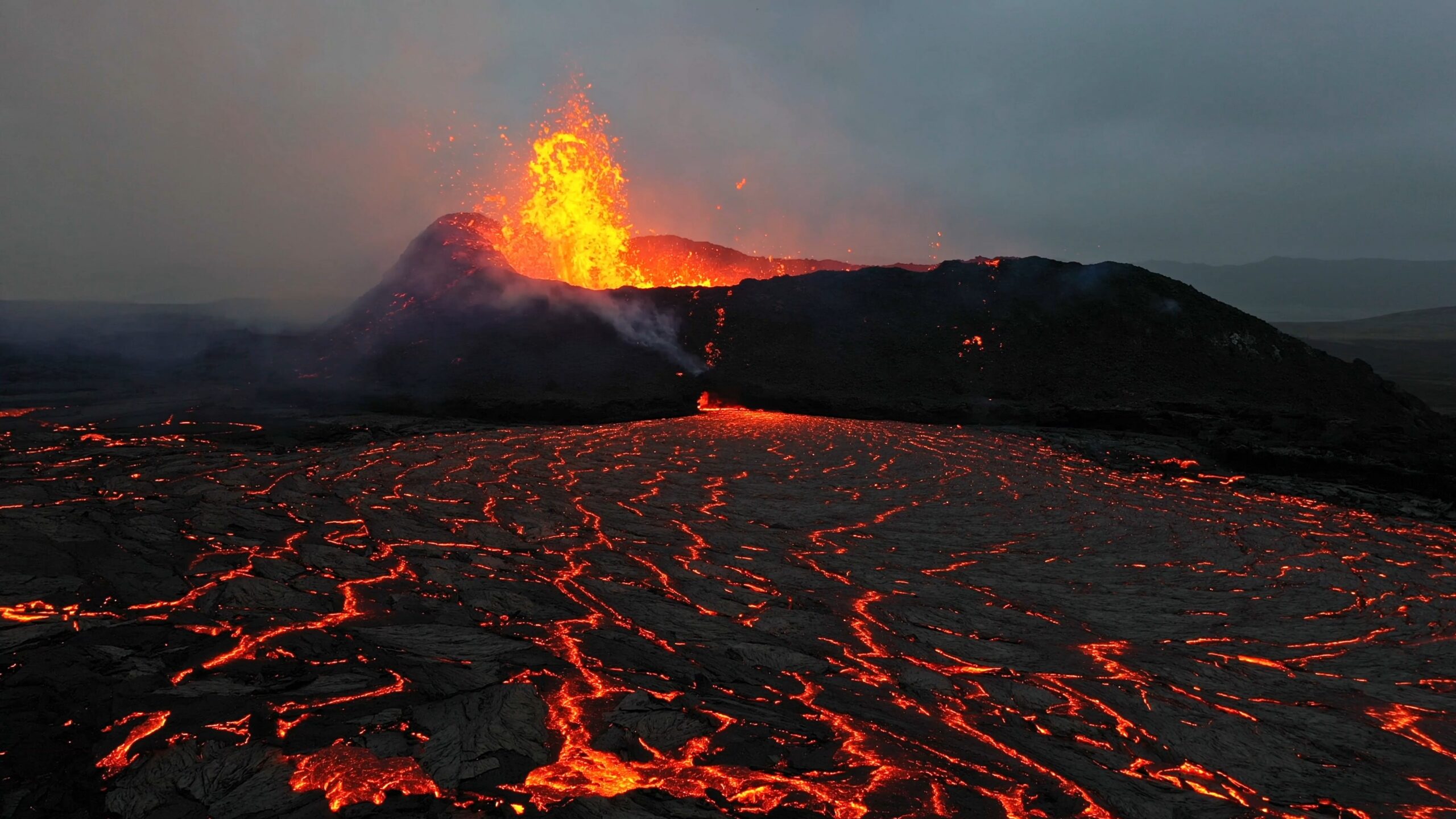An active European volcano in eruption, glowing lava and ash against a dark sky